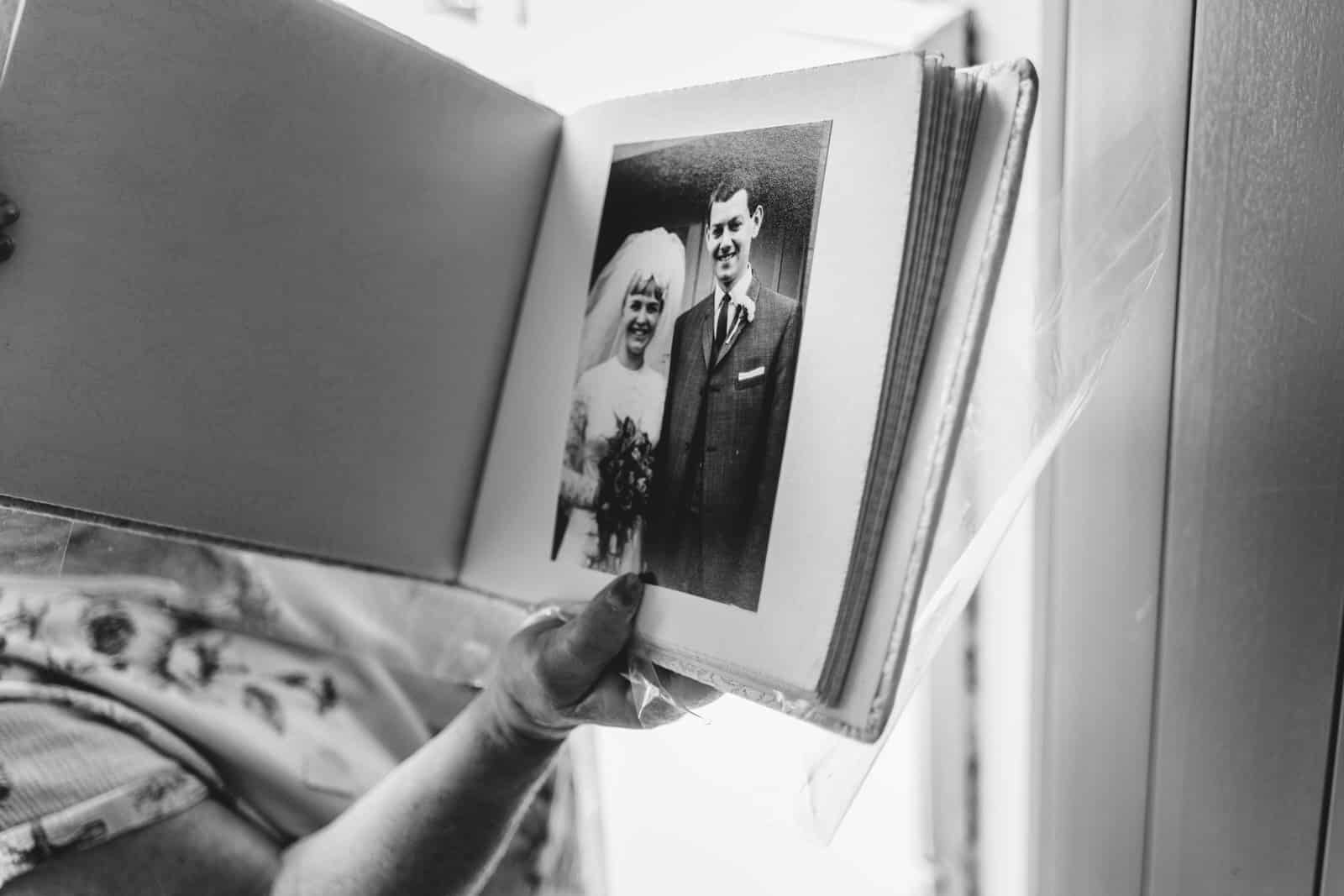 a black and white photo of a woman holding a wedding album.