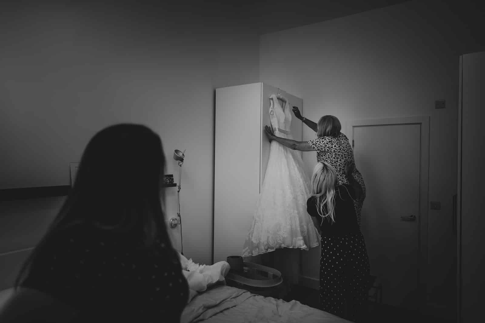 a woman is putting her wedding dress on a dresser.