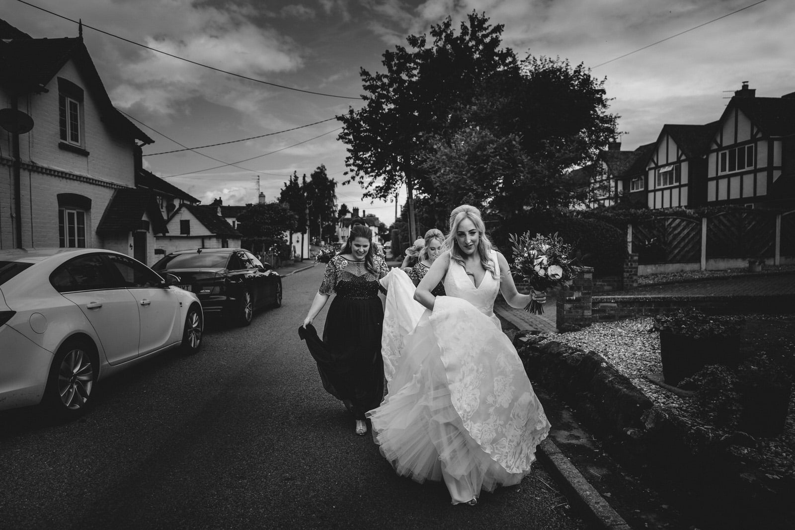 bridesmaids walking down a street in a black and white photo.