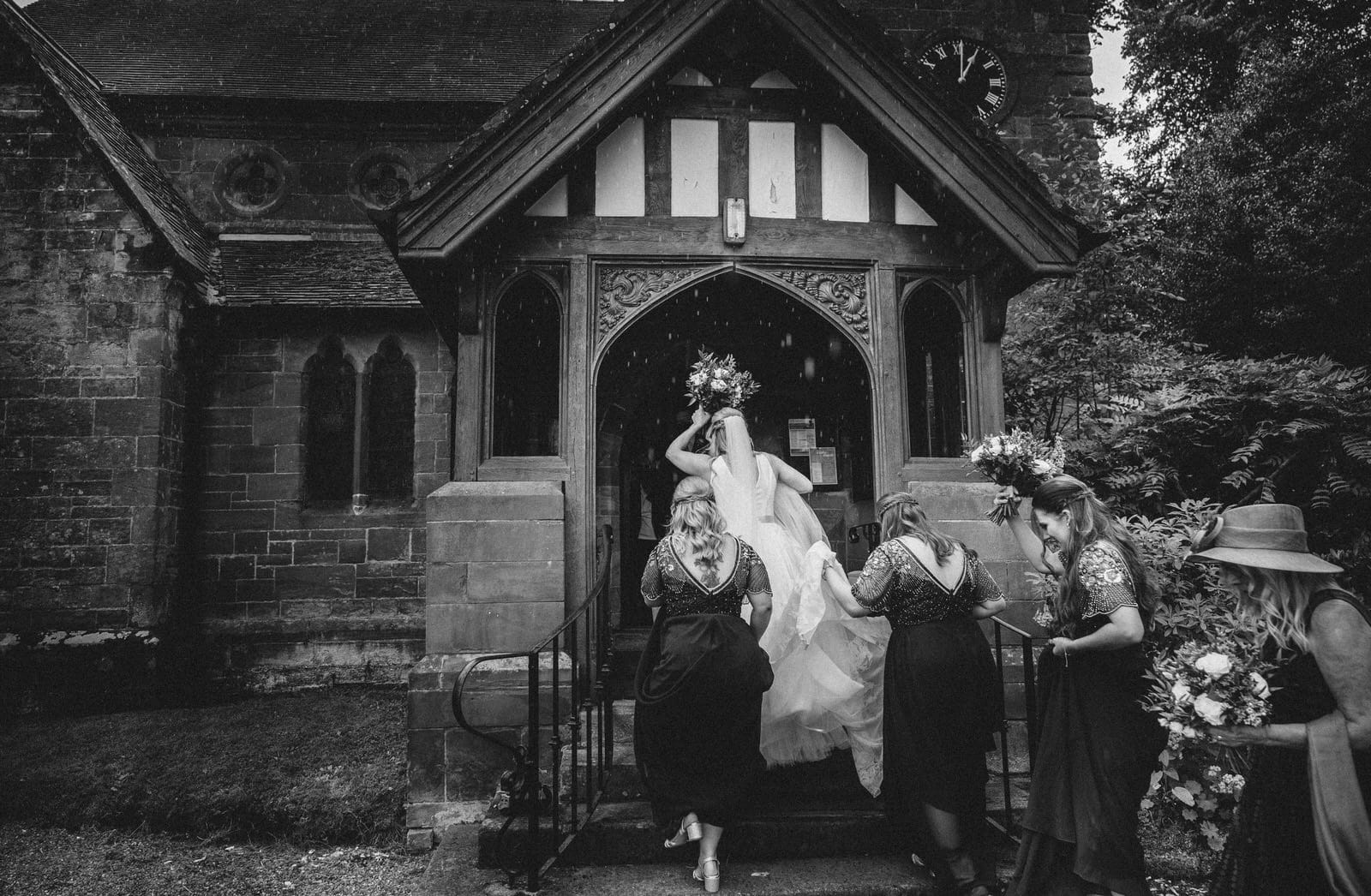 a bride and her bridesmaids are walking out of a church.