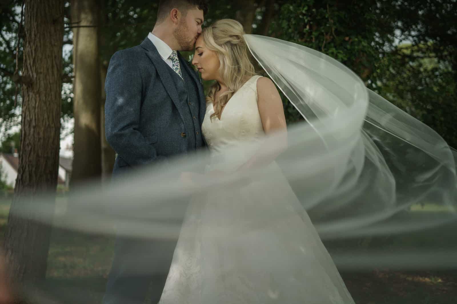 a bride and groom with their veil blowing in the wind.