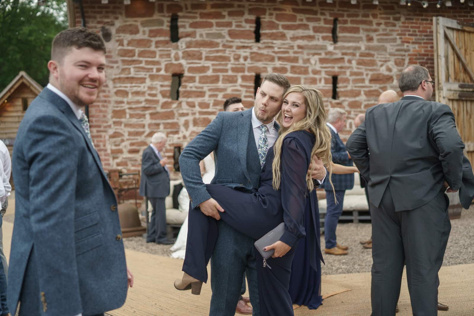 a bride and groom hugging in front of a barn.