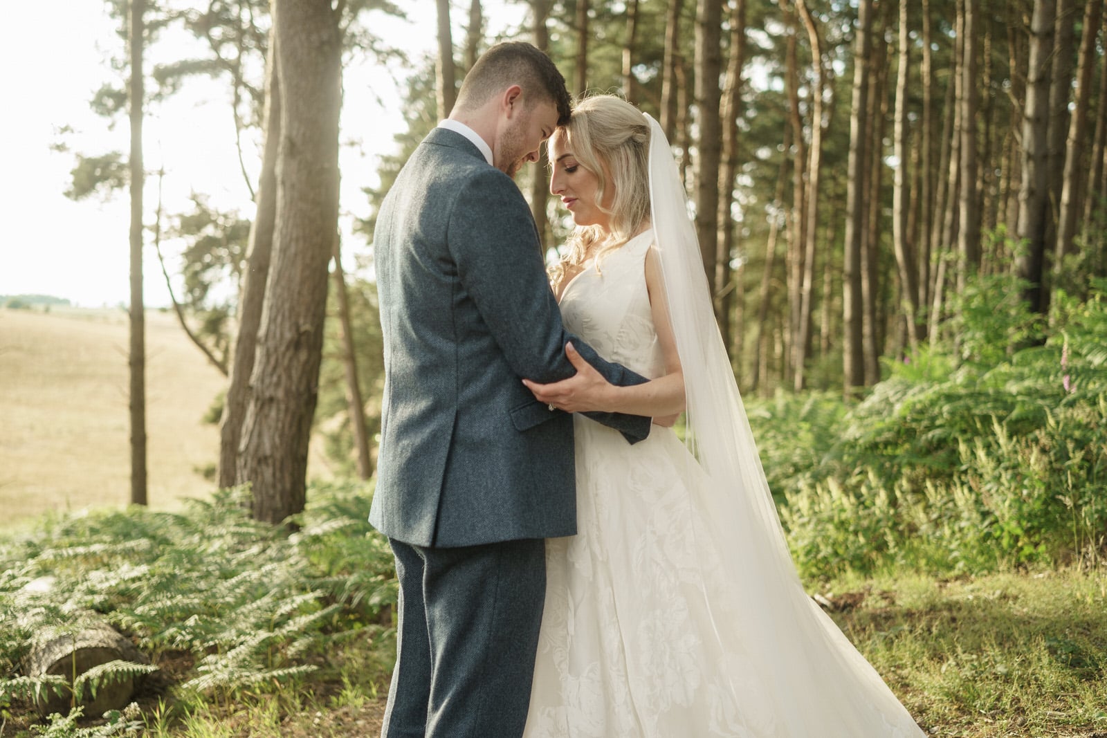 a bride and groom embrace in the woods.