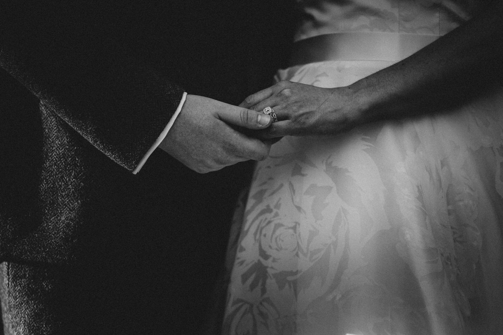 a black and white photo of a bride and groom holding hands.