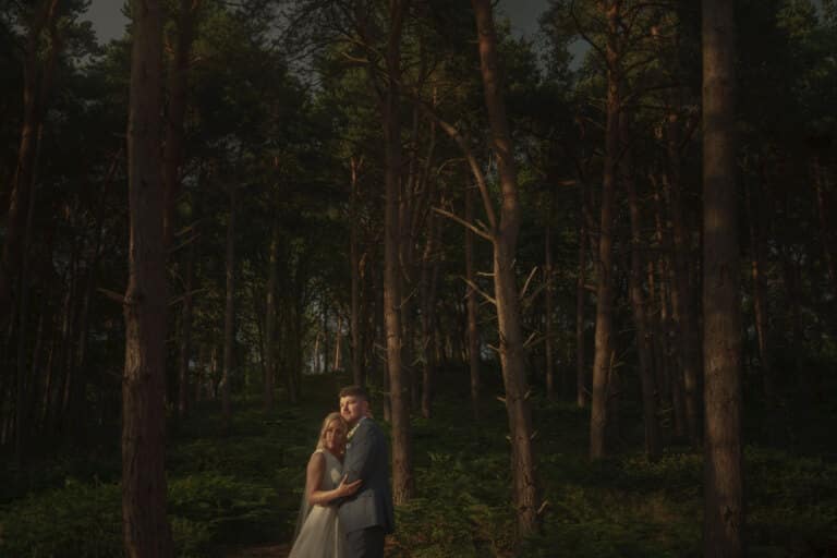 a bride and groom standing in a wooded area.
