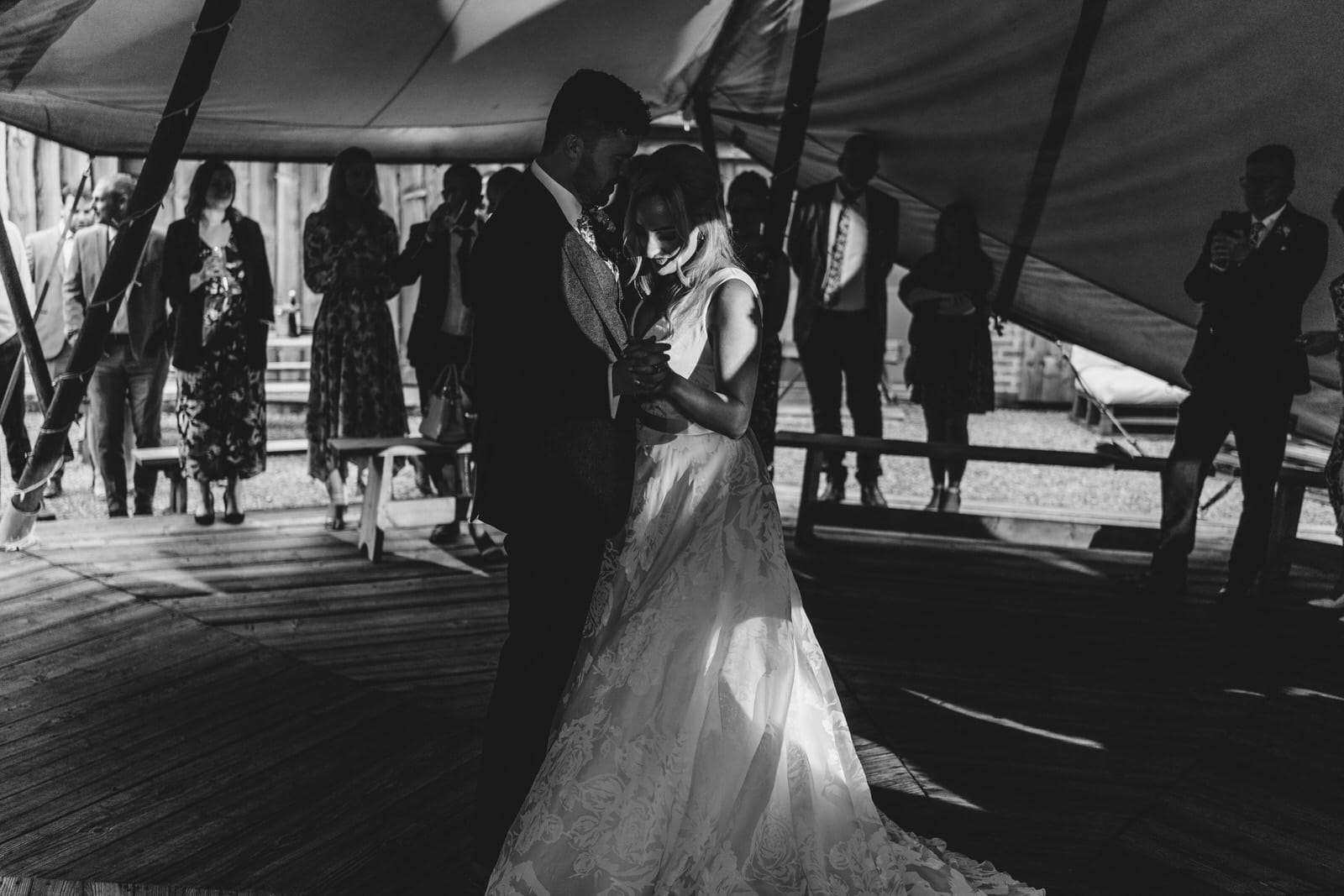 a bride and groom dance in front of a tent.