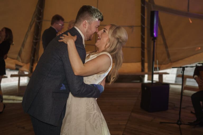 a bride and groom sharing their first dance in a tipi.