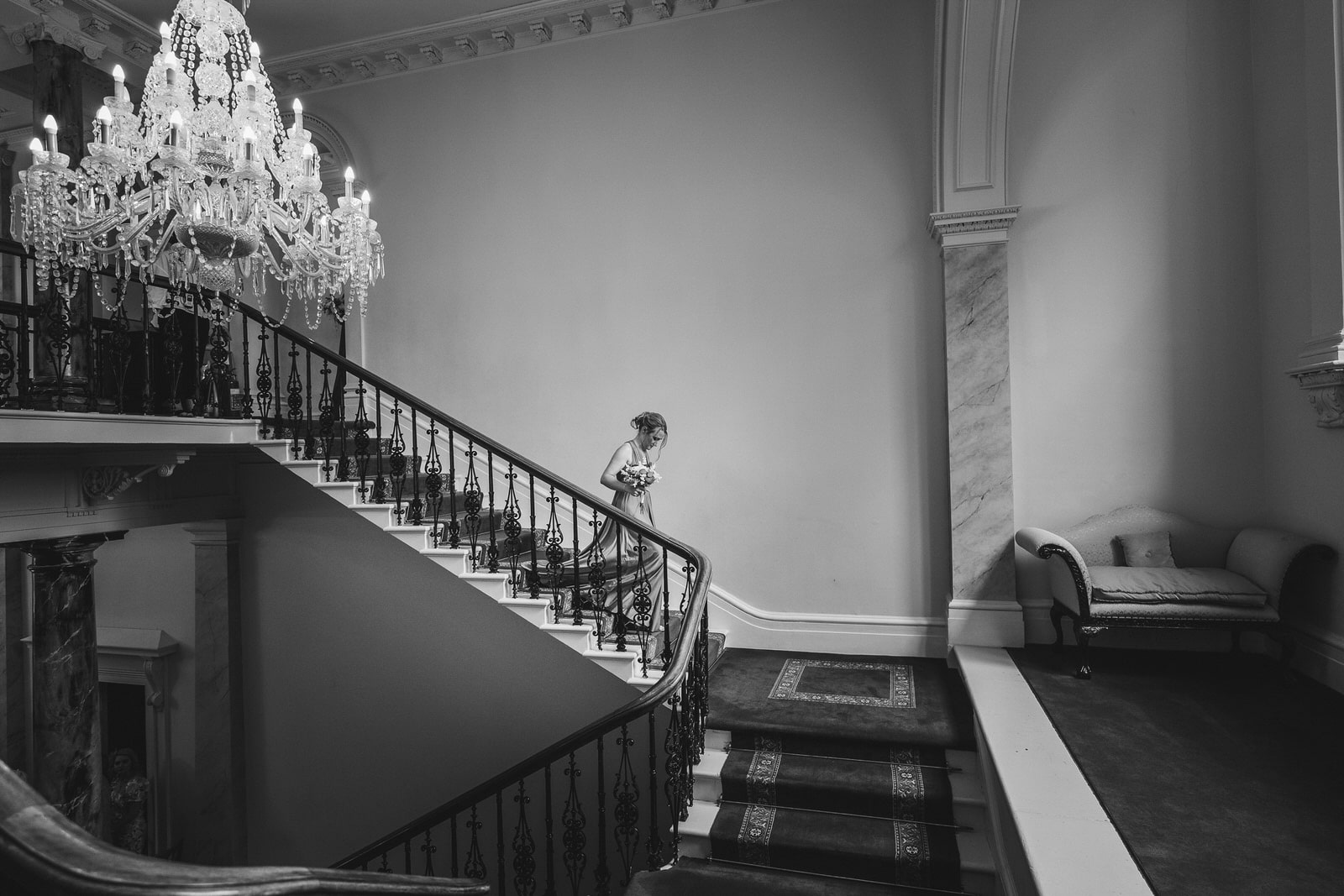 a black and white photo of a staircase with a chandelier.