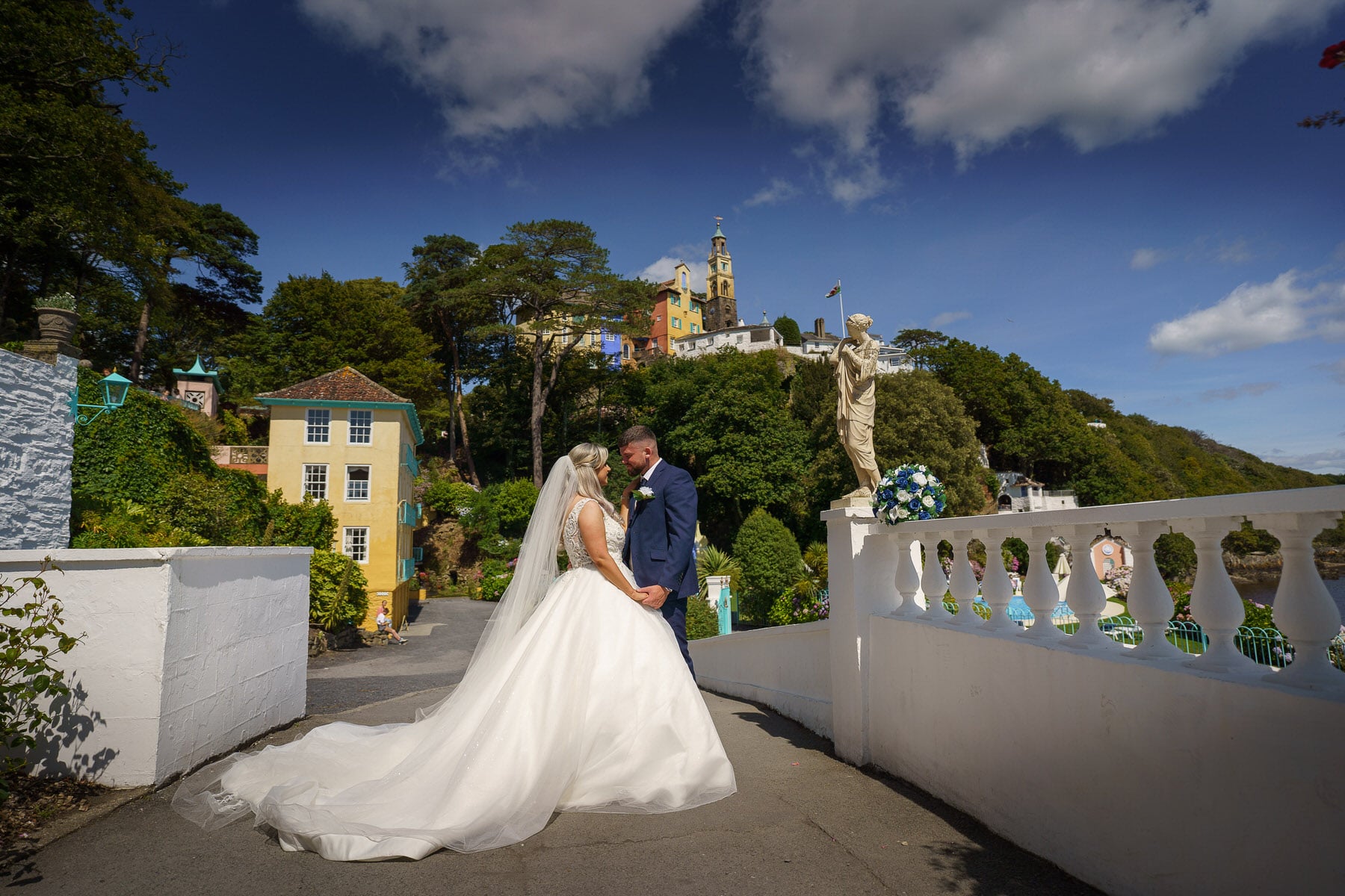 a bride and groom standing on a bridge in front of a castle.