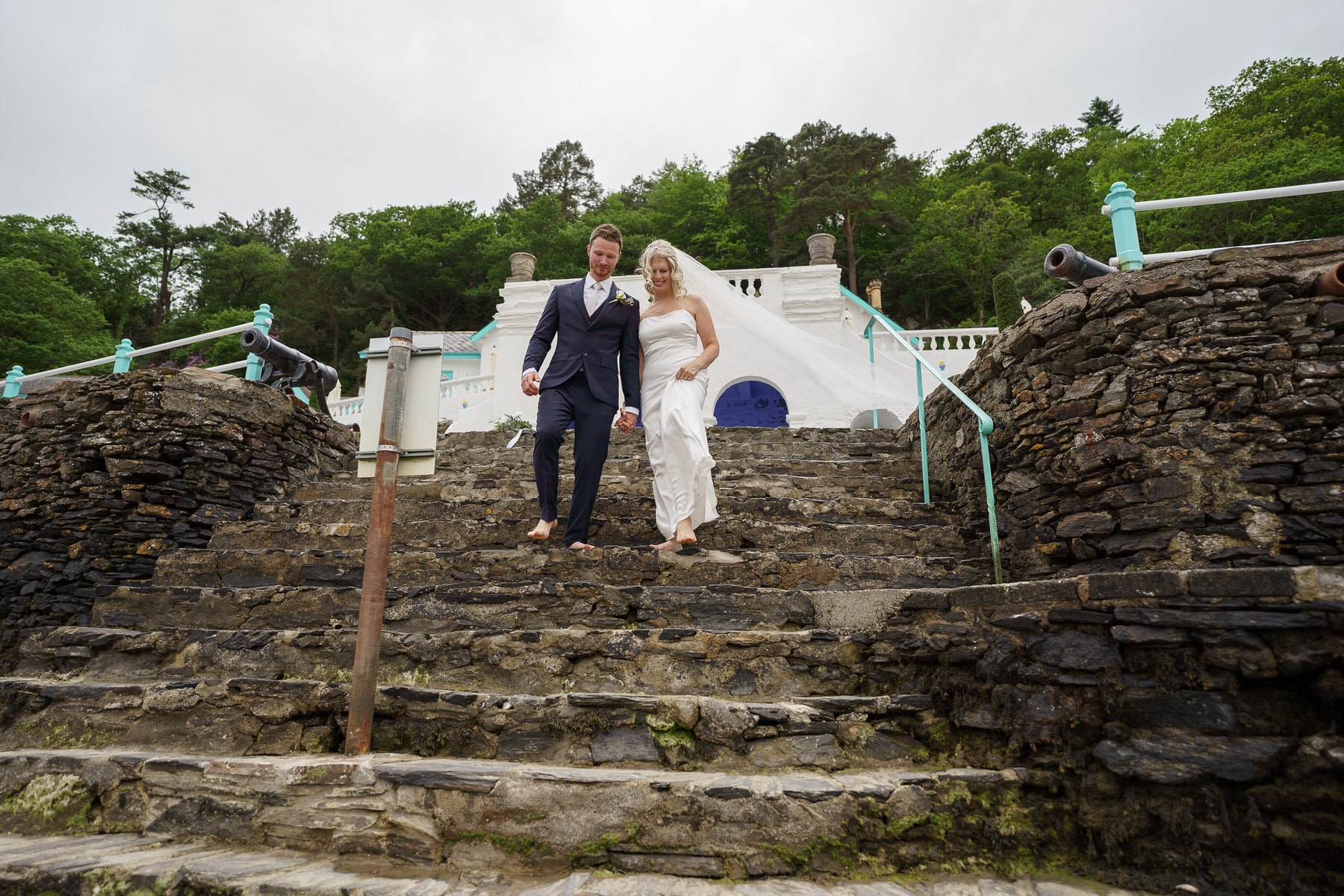 a bride and groom standing on the steps of a stone building.