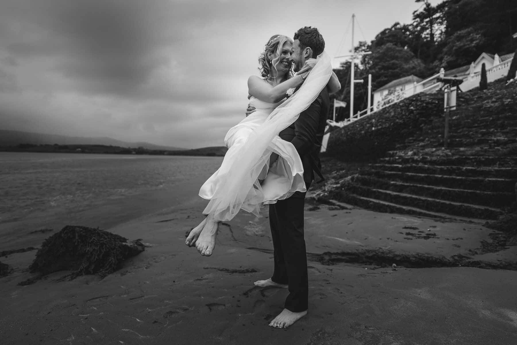 a bride and groom hugging each other on the beach.