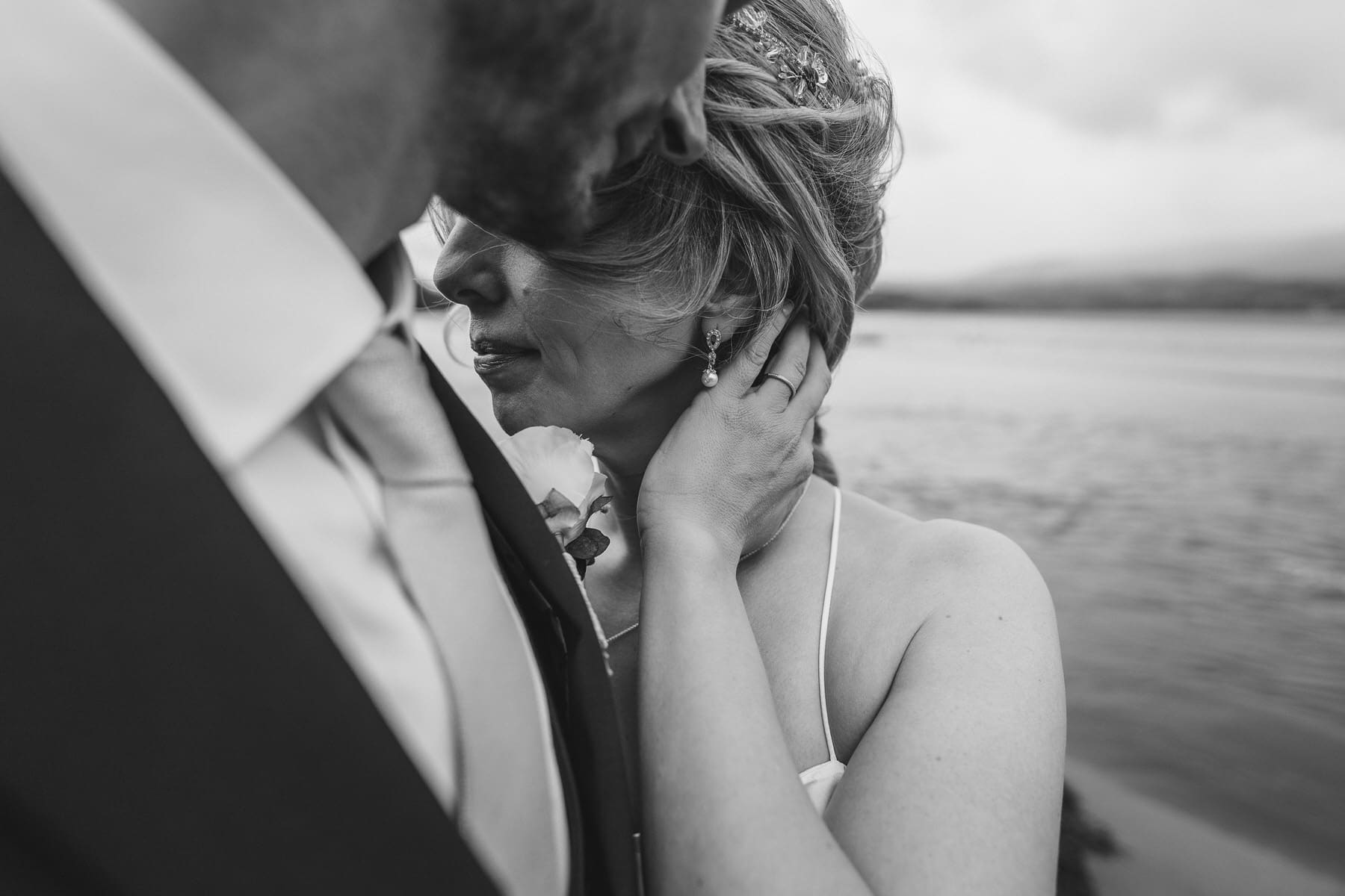 black and white photo of a bride and groom embracing by the water.