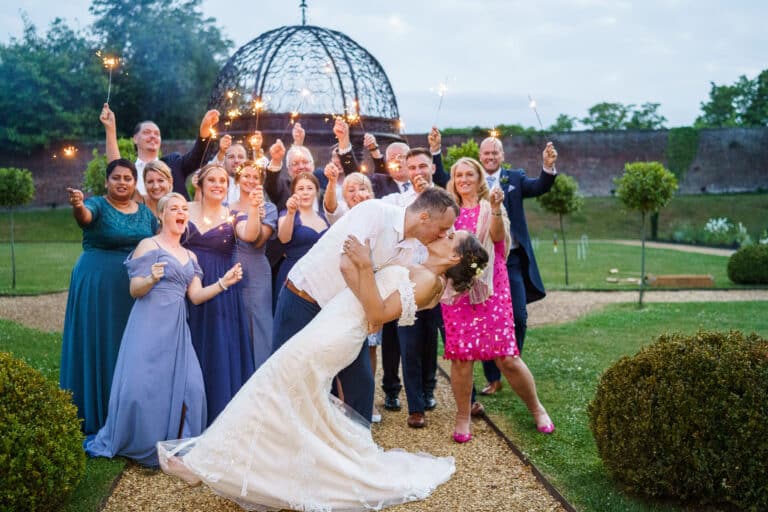 a wedding party at foxtail barns with sparklers in front of a garden.