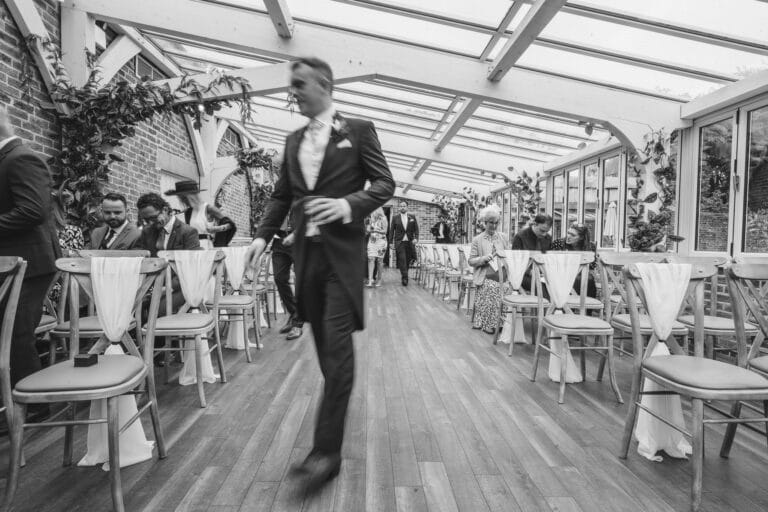 a man strolls down the aisle at a wedding ceremony held in the rustic charm of foxtail barns.