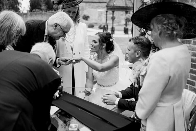 black and white photo of a bride and groom signing a wedding book at foxtail barns.