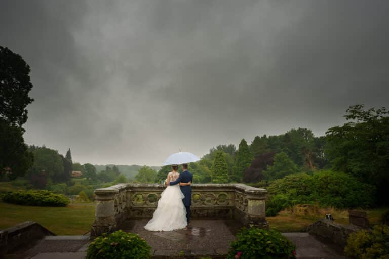 a bride and groom holding an umbrella at foxtail barns under a stormy sky.