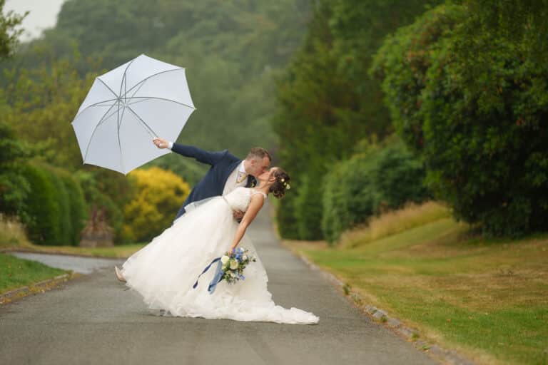 a bride and groom kissing under an umbrella at foxtail barns.