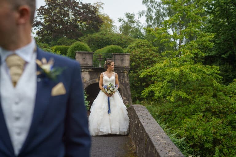 a bride and groom posing elegantly on a scenic bridge.