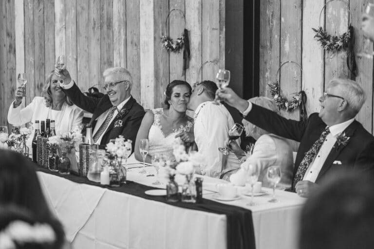 a black and white photo of people toasting at a wedding at foxtail barns.