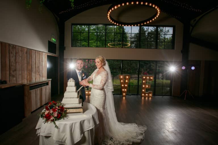 a bride and groom cutting their wedding cake in a large room at foxtail barns.