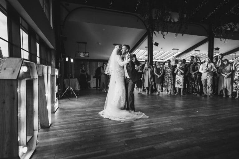 a bride and groom sharing their first dance at foxtail barns, a large room specifically designed for memorable wedding events.