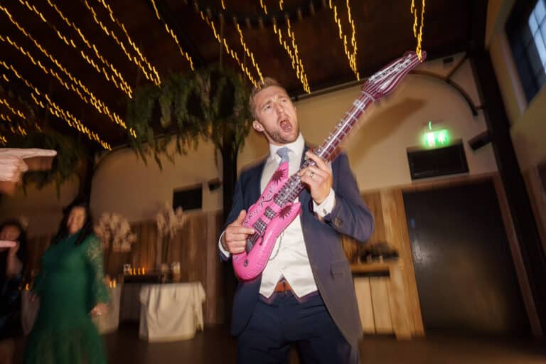 a man playing a pink guitar at a wedding reception at foxtail barns.