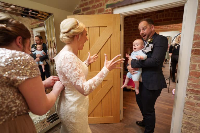 a bride and groom are getting ready in a room at foxtail barns with a baby.