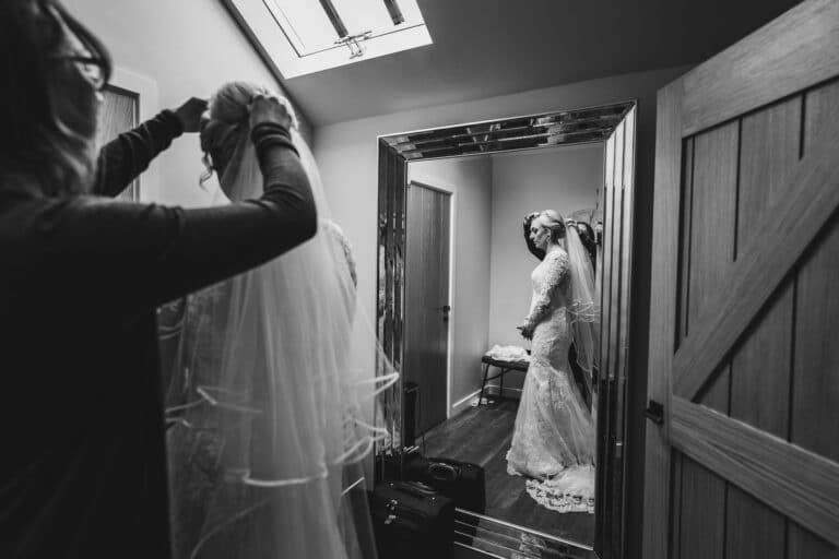 a bride getting ready at foxtail barns, gazing at herself in front of a mirror.