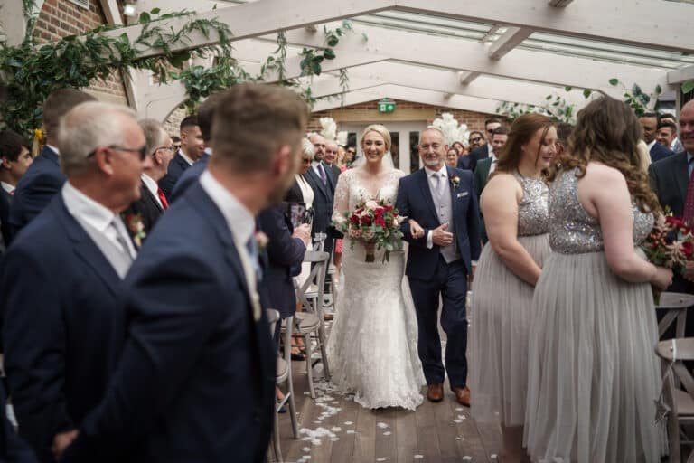 a bride and groom walking down the aisle at foxtail barns on their wedding day.