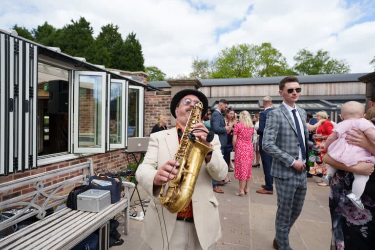 a man playing a saxophone at a wedding ceremony in the elegant foxtail barns venue.