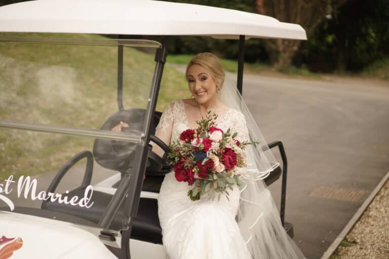 a bride sits in a golf cart at foxtail barns with her bouquet.