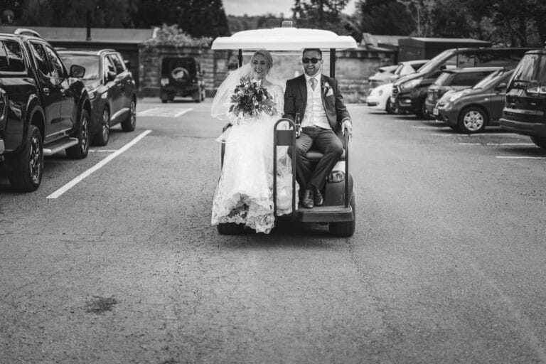 a bride and groom enjoying a fun filled ride in a golf cart at the charming foxtail barns.