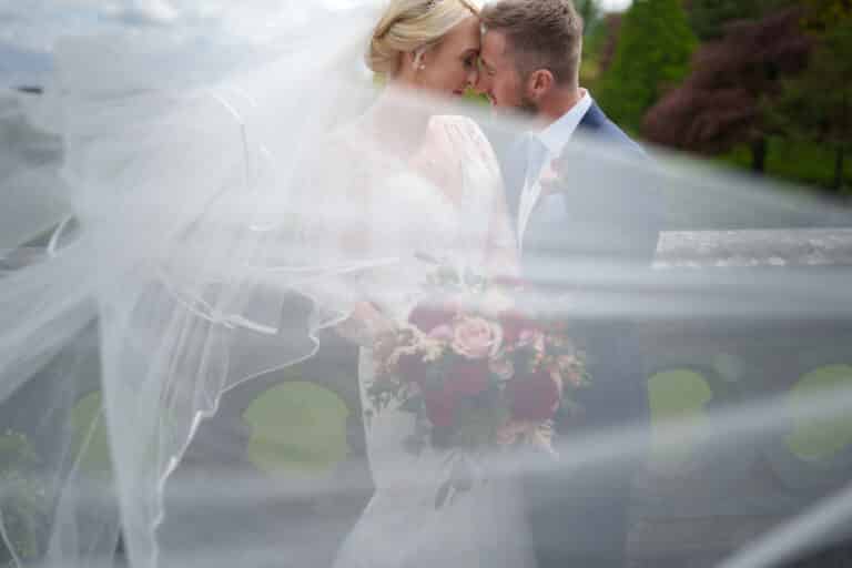 a bride and groom kissing under a veil at foxtail barns.