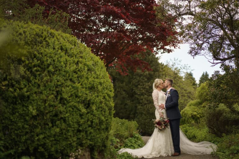 a bride and groom kissing at foxtail barns, a picturesque garden venue.