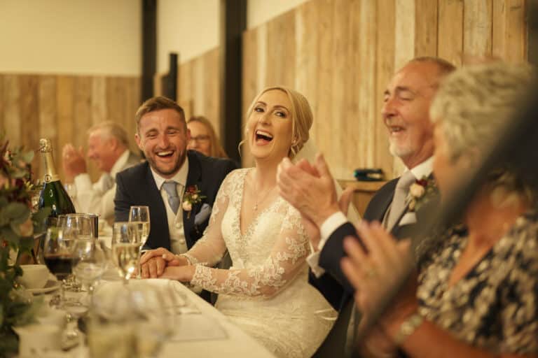 a bride and groom clapping at a wedding reception at foxtail barns.