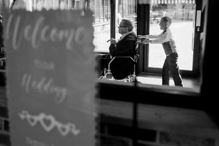 a man in a wheelchair is standing in front of a welcome sign at foxtail barns.