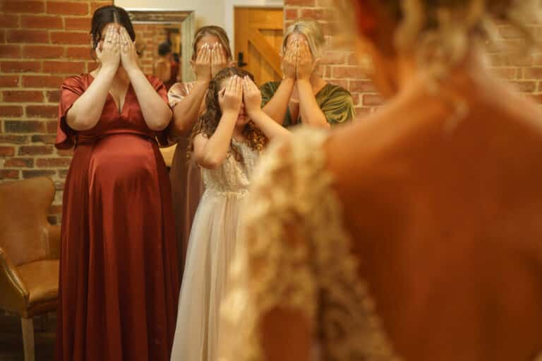 a bride and her bridesmaids getting ready at foxtail barns, looking at themselves in the mirror.