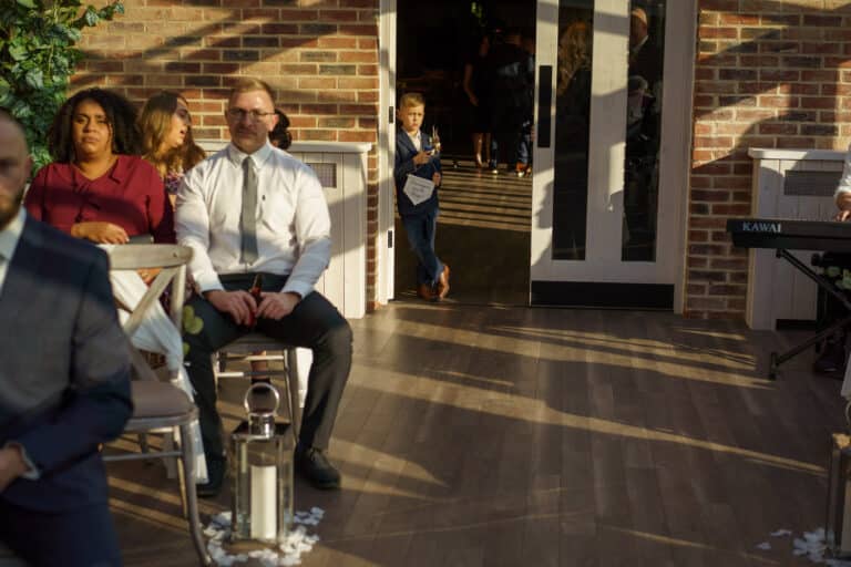 a group of people sitting in chairs at a foxtail barns wedding ceremony.