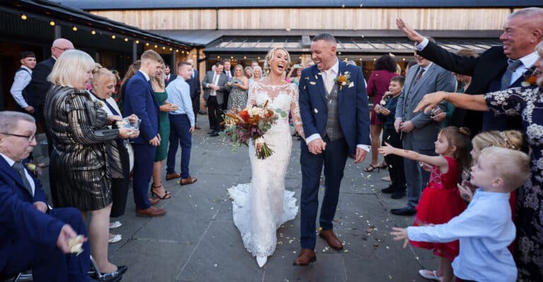 a bride and groom walking through confetti at a foxtail barn wedding.