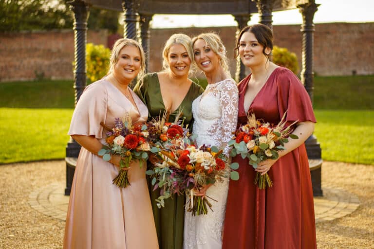 the bride and her bridesmaids pose for a photo in front of a gazebo at foxtail barns.