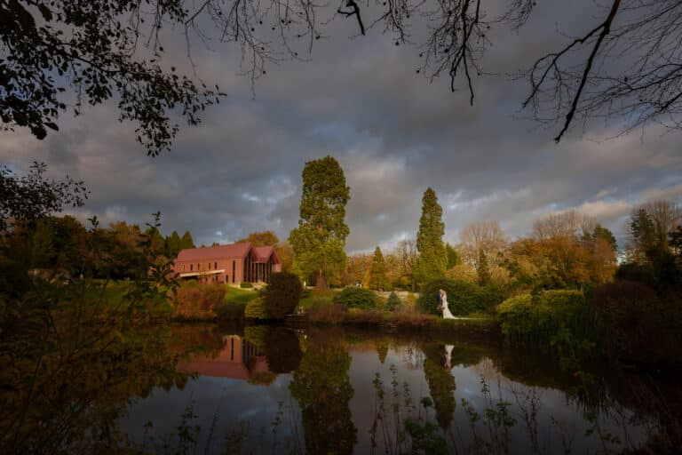a bride and groom standing in front of a pond at foxtail barns.