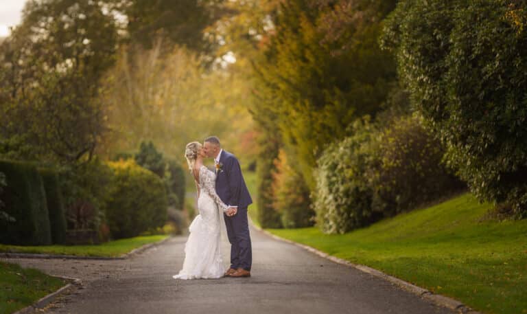 a bride and groom kissing on a path at foxtail barns.