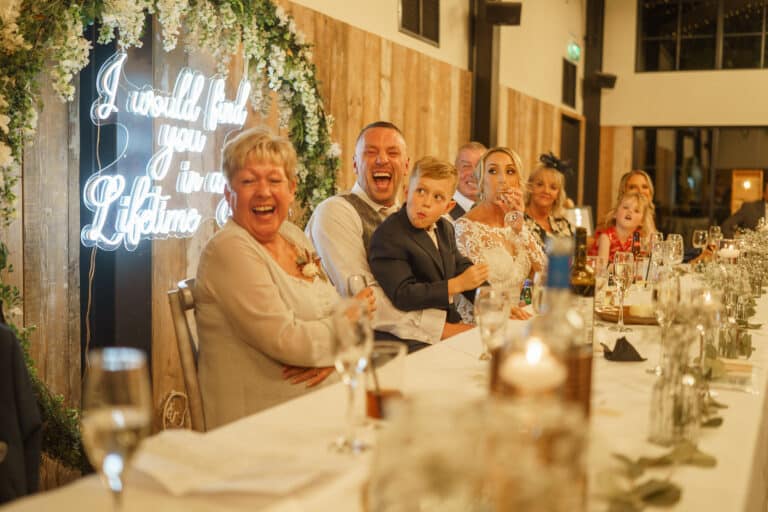 a group of people at a wedding reception in the foxtail barns, sharing laughter and joy.