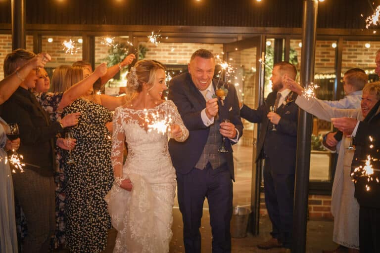 a bride and groom exiting foxtail barns with sparklers in their hands.