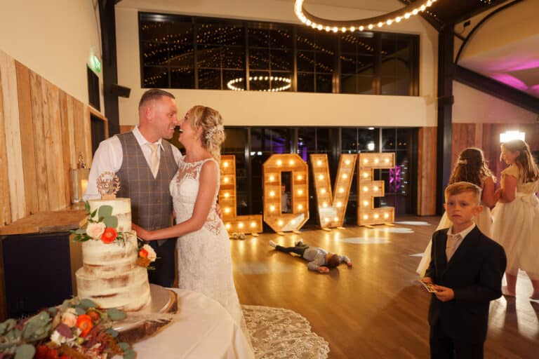 a bride and groom kissing in front of a foxtail barns inspired cake.