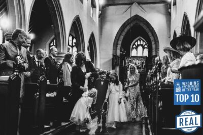 a bride and groom captured by pbartworks photography as they walk down the aisle in a church.