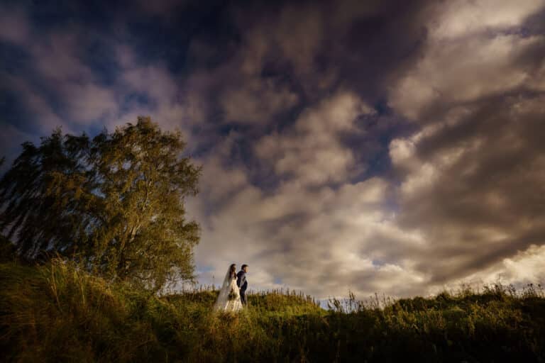 an intimate wedding with a bride and groom standing under a cloudy sky at grain loft.