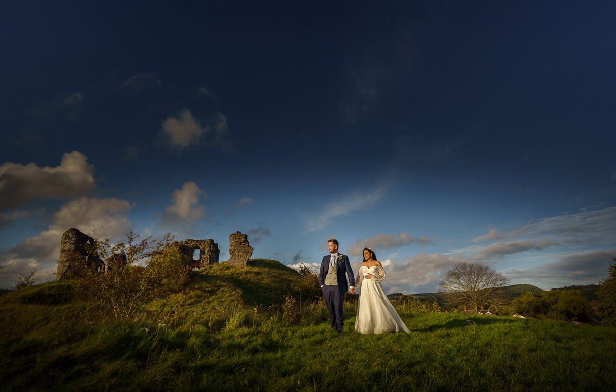 an intimate wedding with a bride and groom standing in a field with a castle in the background.