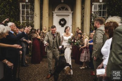 a shropshire wedding photographer captures the special moment of a bride, groom, and their beloved dog walking down the aisle.