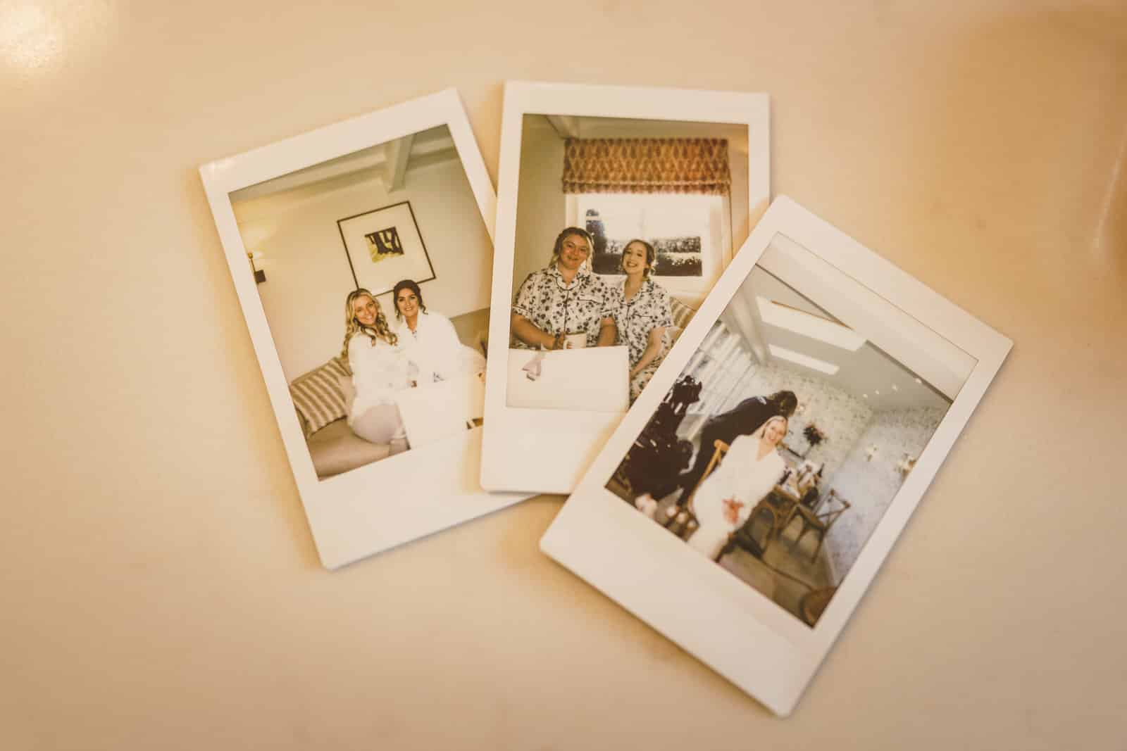three polaroid photos are laid out on a flat surface. each photo, captured at a charming wedding in georgia, depicts different pairs of people, including hamish, posing and smiling for the camera.